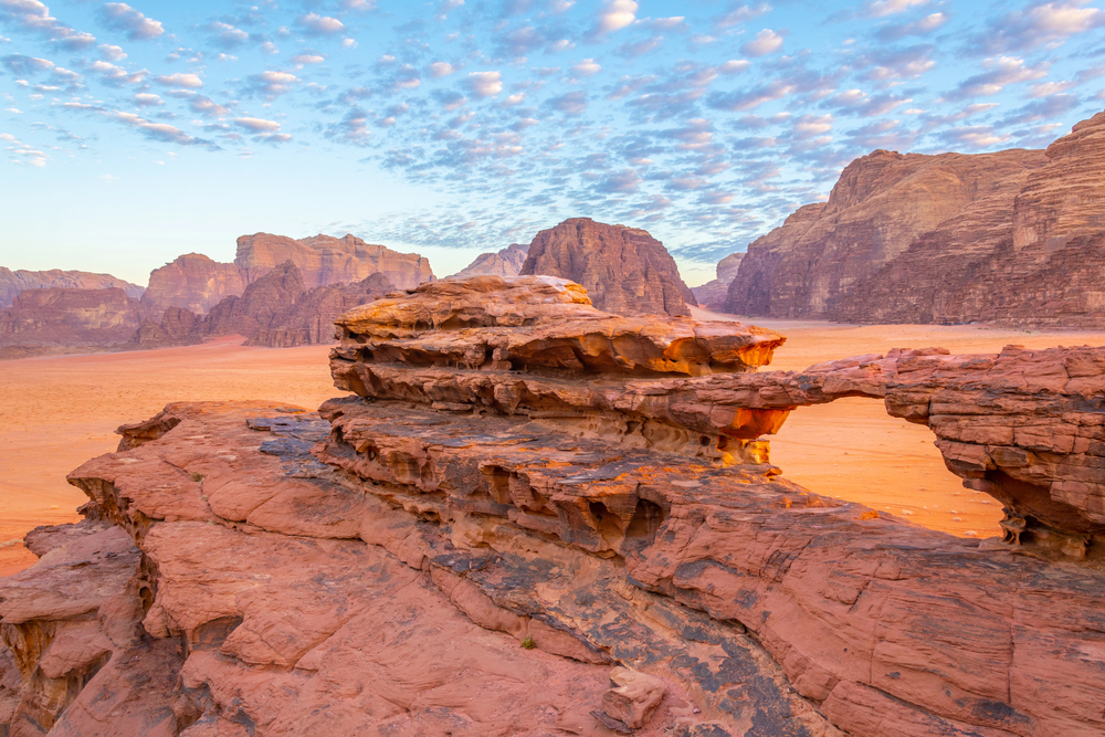 Explore Wadi Rum, Jordan, known for its dramatic desert landscapes, towering sandstone mountains, ancient petroglyphs, and the iconic red sand dunes, often referred to as the Valley of the Moon