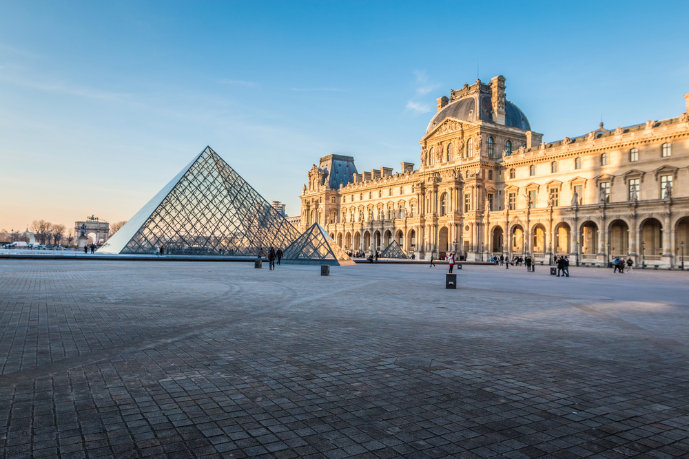 Visitors viewing the Mona Lisa inside the Louvre Museum with surrounding artwork and museum lighting, Paris, France
