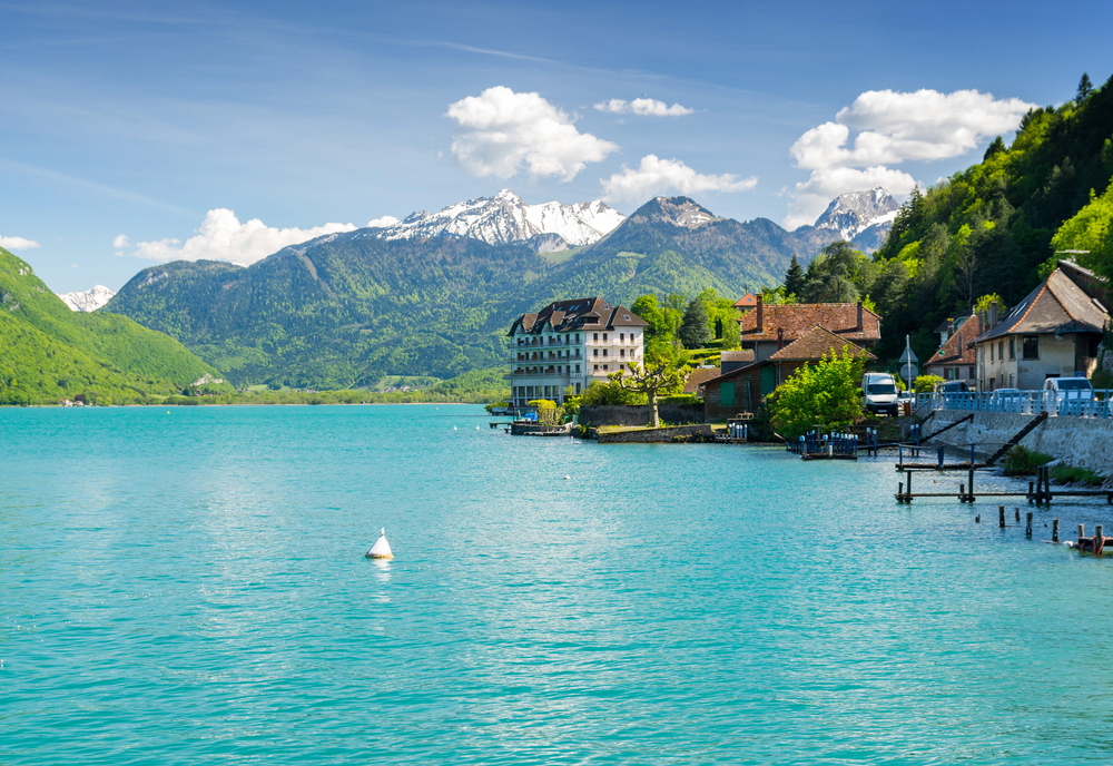 Colorful canal with arched bridges and Alpine houses in Annecy’s Old Town, reflected in Lake Annecy, France