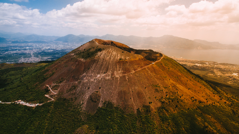 Ruins of Pompeii with Mount Vesuvius rising in the background under a clear blue sky in Italy