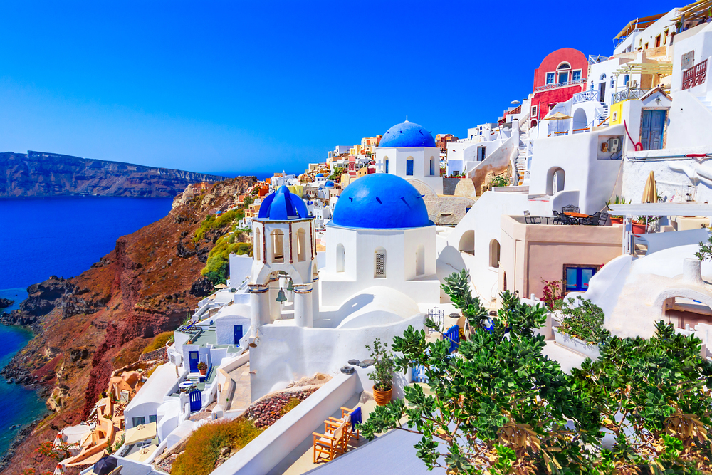 Whitewashed buildings with blue domes overlooking the sea in Oia, Santorini at sunset, Greece