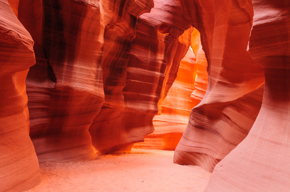 Sunlight beaming through the smooth sandstone curves of Antelope Canyon with glowing red walls in Arizona, USA