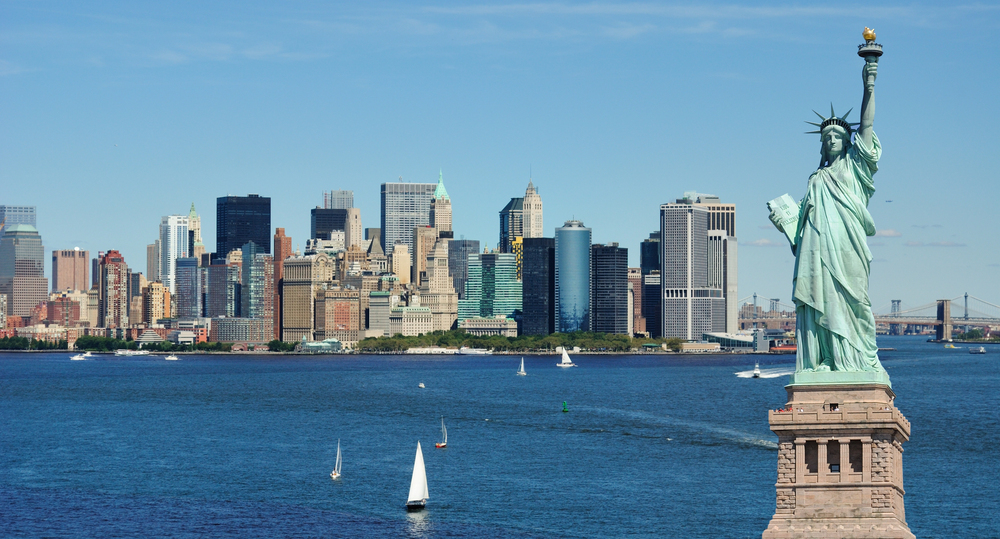 Tour boat passing the Statue of Liberty with the New York City skyline in the background on a sunny day, USA