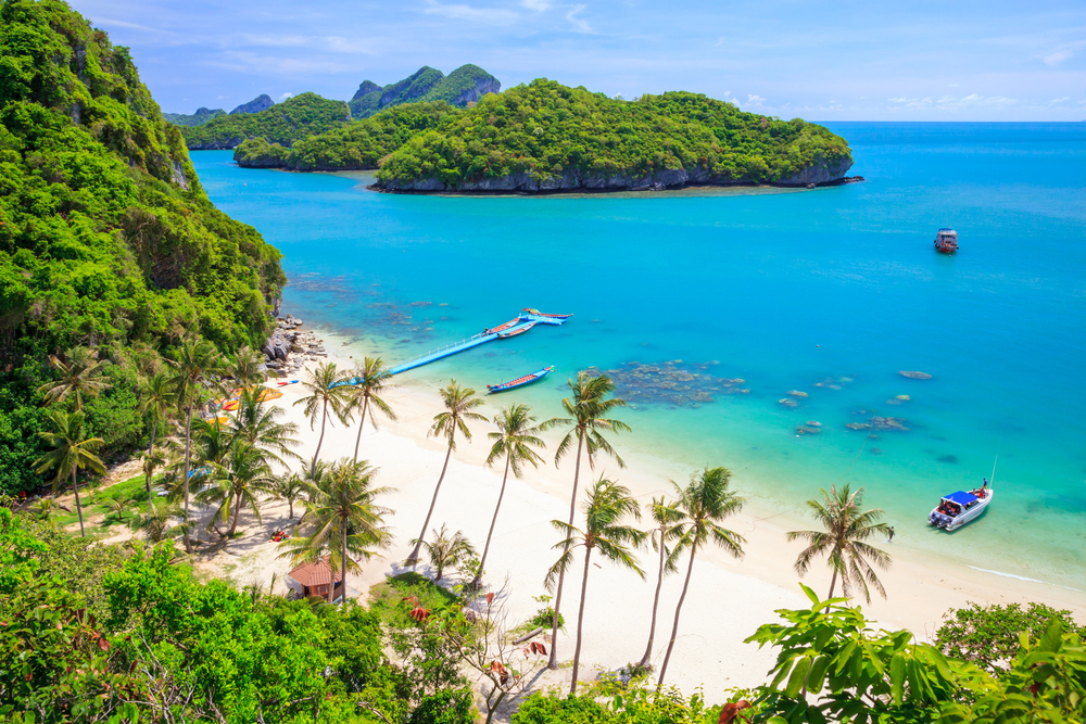 Aerial view of Koh Nang Yuan's sandbar and turquoise water, with green islands and snorkeling boats near Koh Tao, Thailand