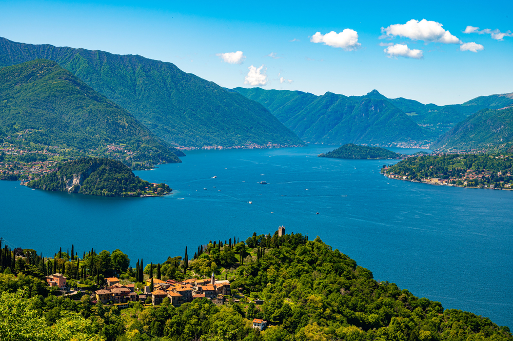 Private boat cruising on Lake Como with hillside villas and Bellagio village in the background, Italy
