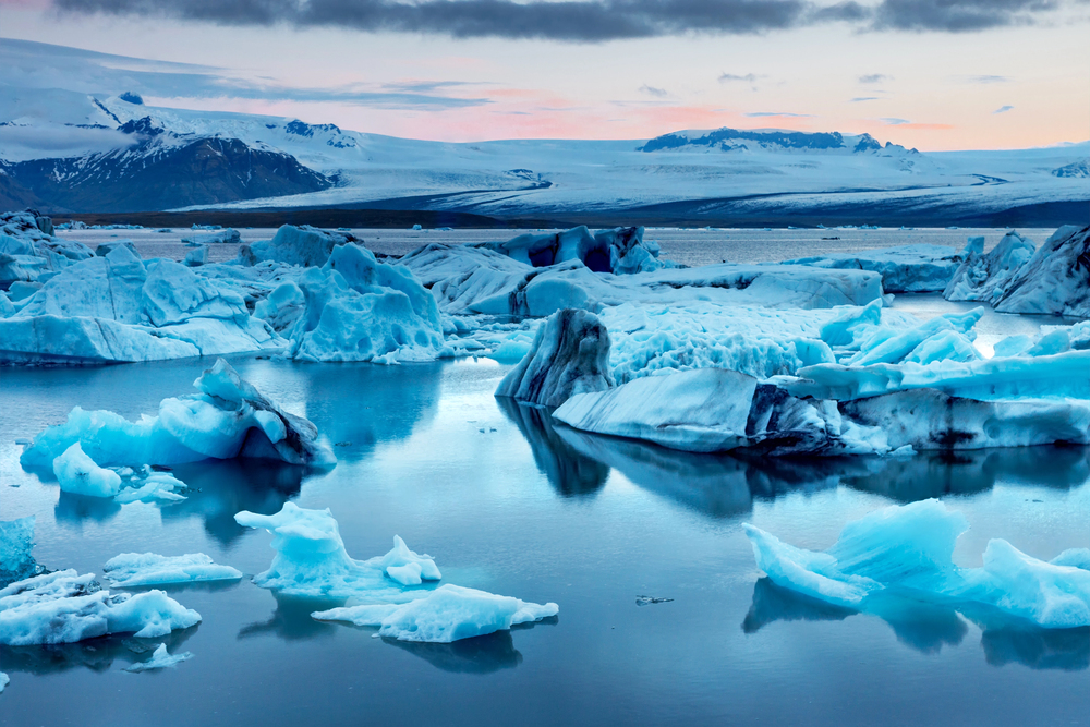 Icebergs floating in Jökulsárlón Glacier Lagoon with black sand and ice shards at Diamond Beach in Iceland